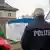 Полицейский стоит перед домом одного из подозреваемых в Бергиш-Гладбахе, осень 2019 года