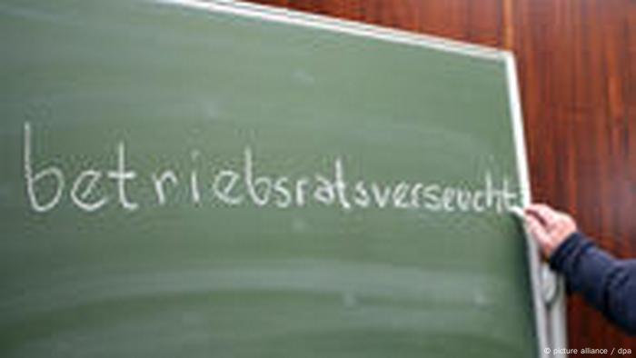 Jemand schreibt mit Kreide das Wort betriebsratsverseucht auf eine Tafel (picture alliance / dpa)