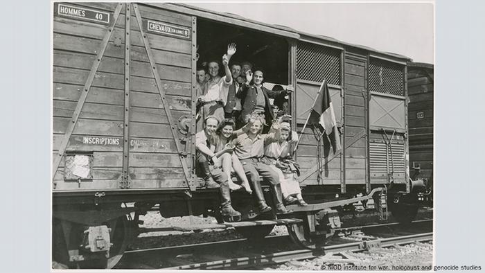 In this photo from May 1945, former forced laborers from France sit on a train car in Braunschweig, Germany — awaiting repatriation to France after the Allied liberation