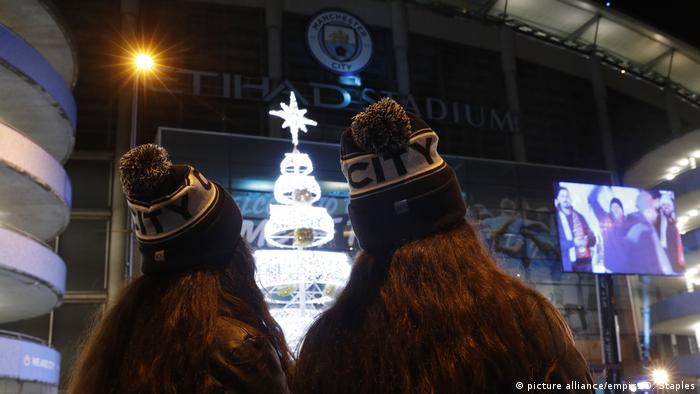 Two women look up at an illuminated Christmas tree in Manchester 