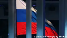 ARCHIV - 07.03.2014, Russland, Sotschi: ILLUSTRATION - Eine Flagge Russlands weht hinter einem Zaun während der Eröffnungsfeier der Paralympischen Spiele 2014 im Fisht Olympiastadion. Die unabhängige Prüfkommission der Welt-Anti-Doping-Agentur (CRC) hat dem Exekutivkomitee der WADA empfohlen, die russische Agentur wegen Manipulation von Dopingdaten aus dem Moskauer Labor wieder zu sperren. Foto: Jan Woitas/zb/dpa +++ dpa-Bildfunk +++ | Verwendung weltweit
