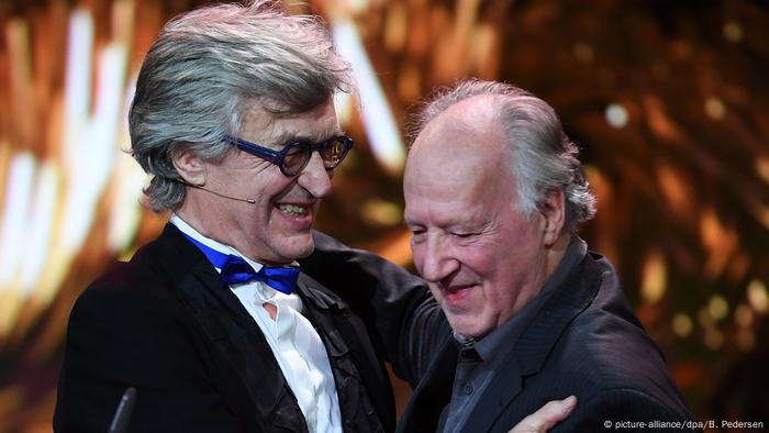 Wim Wenders und Werner Herzog umarmen sich lächelnd