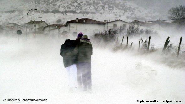 Drei Personen halten sich aneinander fest und kämpfen sich durch den Schneesturm (Foto: dpa)