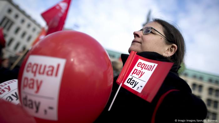 Ein Demonstrant hält in Berlin bei der Demonstration zum gleichen Zahltag am 18. März 2019 Flaggen und Luftballons für den gleichen Zahltag