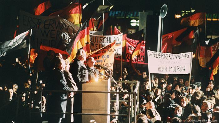 People holding German flags and banners outside with West German chancellor Helmut Kohl in 1989.