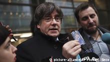 Catalonia's former regional president Carles Puigdemont, center, shows his badge to journalists as he stands next to former Catalan regional minister Antoni Comin outside the European Parliment in Brussels, Friday, Dec. 20, 2019. In a potentially stinging reversal for Spanish justice authorities, the European Union's top court ruled that a former Catalan official serving a prison sentence for his role in a banned independence referendum two years ago had the right to parliamentary immunity when he was on trial. (AP Photo/Francisco Seco) |