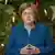 Angela Merkel stands before a Christmas tree