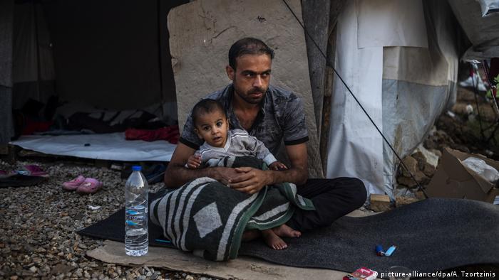 Ein Mann sitzt mit einem Kind vor einer Unterkunft im Flüchtlingslager Moria auf der griechischen Insel Lesbos