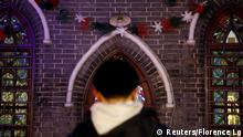 A man stands in front of Christmas decorations at Xishiku Cathedral, a government-sanctioned Catholic church, on Christmas Eve in Beijing, China December 24, 2019. REUTERS/Florence Lo