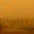 Faxineiro limpa pátio do Parlamento em Camberra numa imagem amarelada devido à fumaça