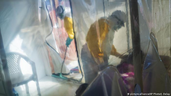 Health workers wearing protective suits look after an Ebola victim