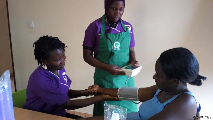 Two nurses perform a check-up on a young pregnant woman in Uganda