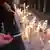 Foto simbólica de mujeres encendiendo velas blancas en señal de luto