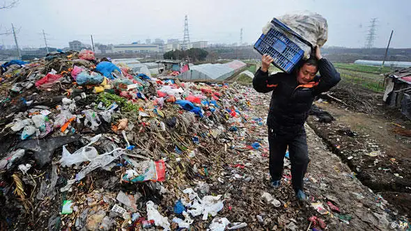 In this photo taken Monday, Feb. 1, 2010, a farmer walks past a garbage dump site near a village in Hefei, in central China's Anhui province. (AP Photo) ** CHINA OUT **