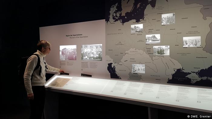 A person looking at a multimedia museum display, showing different screens and a map of Europe.