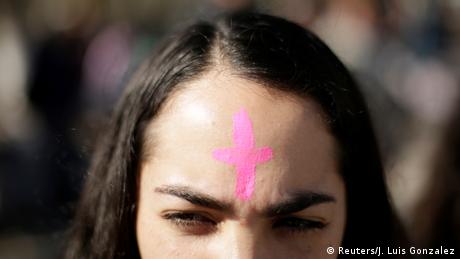 A woman with a pink cross on her forehead