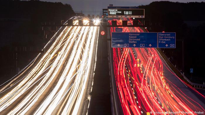 Streams of red and white lights created by cars in motion illuminate a dark high