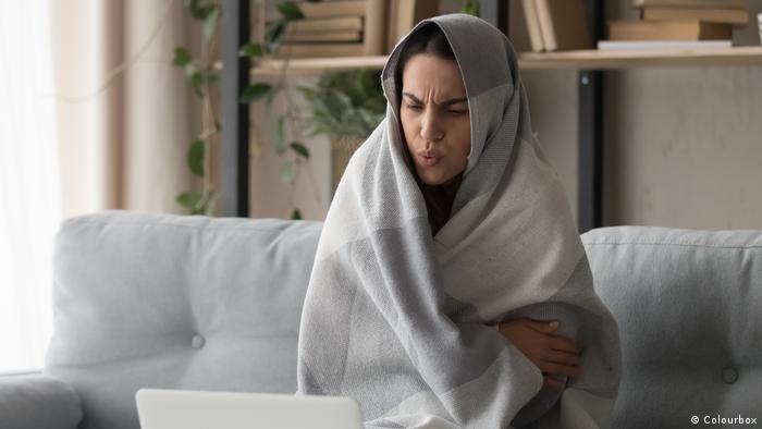 Žena ogrnuta u deku pred prijenosnim računalom