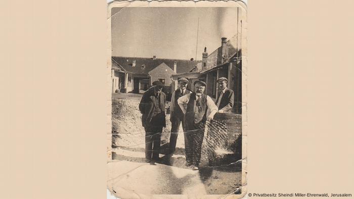 Uma foto histórica mostra quatro homens parados junto a uma cerca