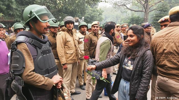 A female protester holds a flower at a soldier during an protest in New Delhi