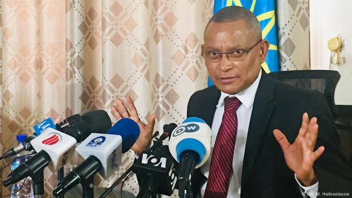 TPLF leader Debretsion Gebremichael stands in front of a bank of microphones