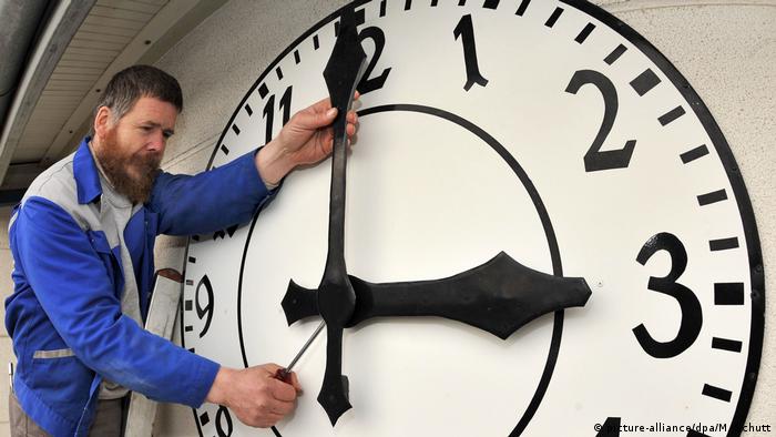 Чоловік переводить стрілки великого годинника (символічне фото)