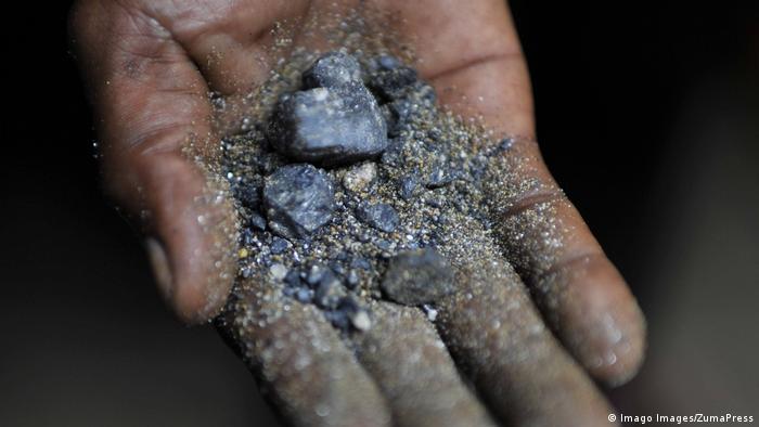 A miner holds raw coltan in his hand