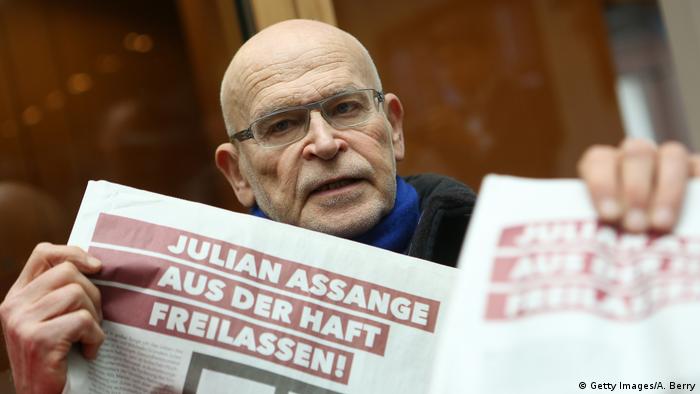 Günter Wallraff holding a newspaper with a headline reading Release Assange from prison!