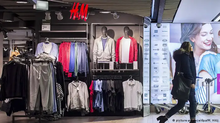 A woman walks past an H&M store where clothes are on display