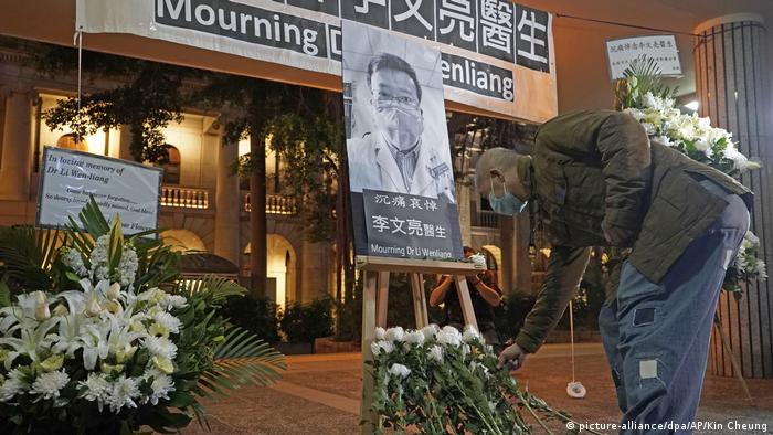A man lays flowers in front of a photo of Li Wenliang