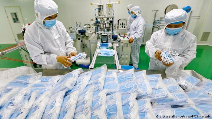 Workers pack medical masks in plastic