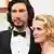 Schauspieler Adam Driver in Anzug und mit Fliege steht neben seiner Frau Joanna Tucker, Haare blond gewellt, und lässt sich auf dem roten Teppich fotografieren.