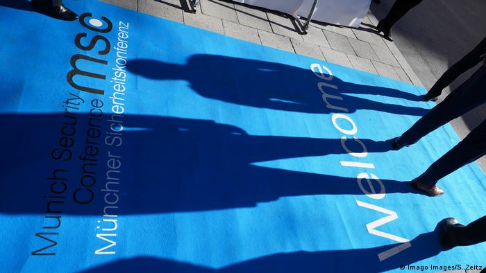 Shadows of people fall on the logo of the Munich Security Conference