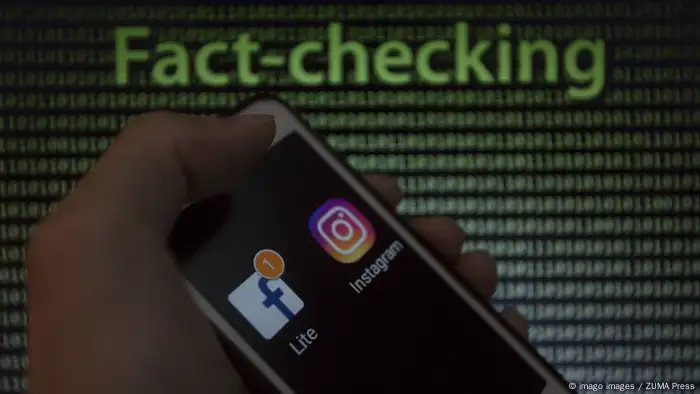 A hand is shown holding a smartphone displaying the Facebook and Instagram logos