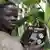 Boy smiles as he holds a radio set in a banana plantation