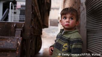Criança síria observa seus parentes carregando pertences em caminhão antes de deixarem a cidade de Binnish, no noroeste da província de Idlib