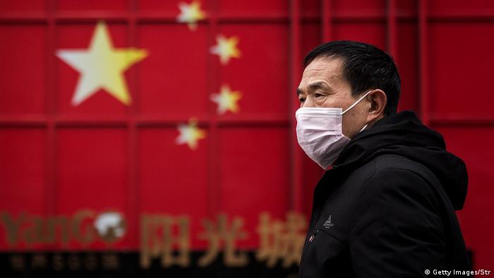 Мужчина в Китае в респираторной маске, призванной защитить его от заражения коронавирусом