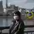 Туристка в маске позирует на фоне олимпийского объекта в Токио