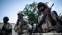 Soldiers conduct the daily flag-lowering ceremony at the Force Multinationale Mixte (FMM) base in Mora, in Cameroon's Far North Region, on September 28, 2018. - Since 2014, the Far North region of Cameroon has witnessed a conflict between the Nigerian Islamic terrorist group Boko Haram and the Cameroonian army. Approximately 100,000 Nigerians have sought refuge in this region, fleeing the violence of the armed group of Abubakar Shekau, in addition to the 250,000 Cameroonian IDPs in that area that has been historically poor and neglected by the central government. (Photo by ALEXIS HUGUET / AFP) (Photo credit should read ALEXIS HUGUET/AFP via Getty Images)