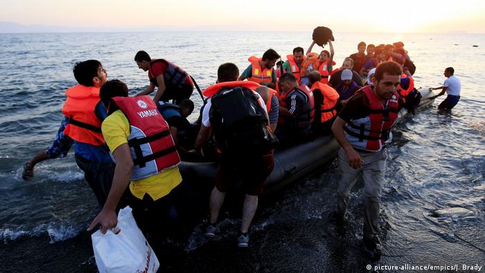 Migrants disembark a dinghy on a beach in Kos, Greece