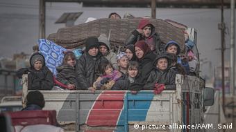 Famílias sírias são vistas em cima de um caminhão com seus pertences a caminho de zonas mais seguras em Idlib