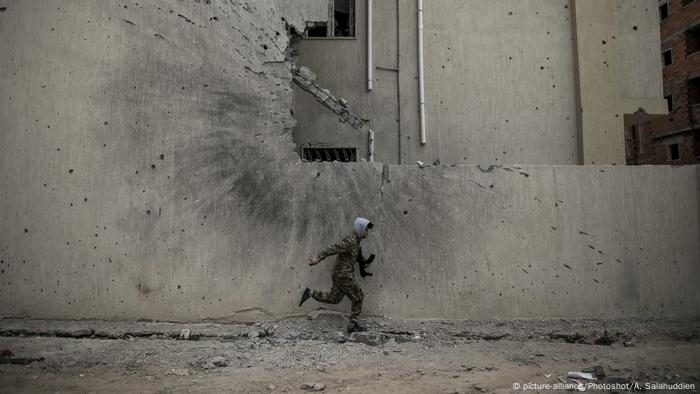 A soldier running to take cover from snipers on a front line in Tripoli, Libya