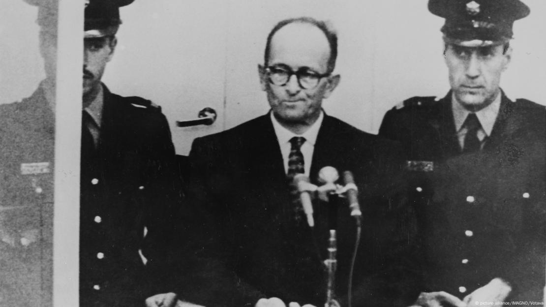 Adolf Eichmann flankerad av poliser vid rättegången i Israel