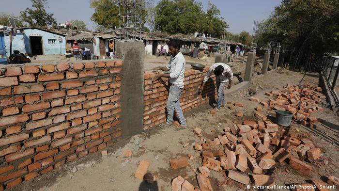 Indian workers construct a wall in front of a slum ahead of Trump's visit to Ahmadabad