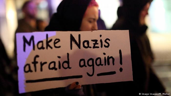 Demonstrator agains racist attack in Hanau holds up sign reading Make Nazis afraid again!