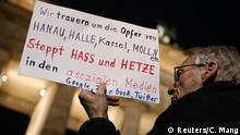 A man holds a poster while attending a vigil for the victims of a shooting that left several people dead in Hanau near Frankfurt, as mourners gather in front of the Brandenburg Gate in Berlin, Germany, February 20, 2020. REUTERS/Christian Mang