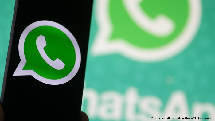 WhatsApp logo displayed on a phone screen, smartphone and keyboard are seen in this multiple exposure illustration