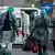 Италия вышла на третье место в мире по числу случаев заражения коронавирусом. На фото мужчина и женщина в защитнгых костюмах сопровождают пожилую даму в респиратороной маске к карете скорой помощи.
