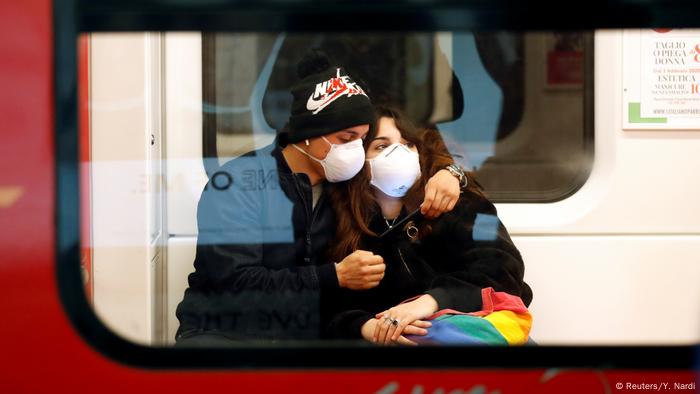 Pareja sentada abrazada, ambas personas con máscaras de respiración