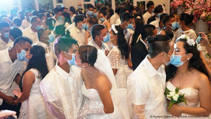 Filipino couples kiss with face masks in mass wedding. 